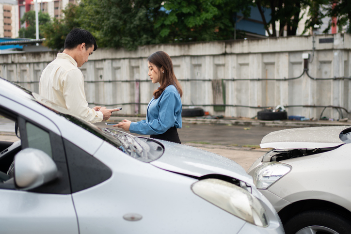 A man and woman involved in a car accident exchange information - Honolulu car accident attorney