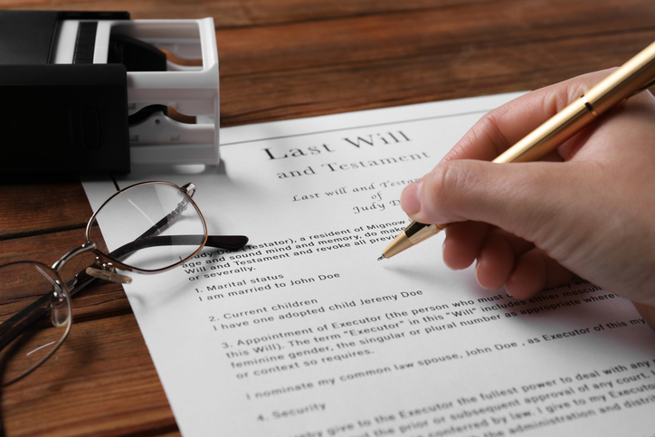 closeup of someone signing a will - what is a will vs. a trust?