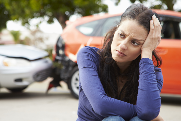 woman sitting beside car accident scene - am i liable if my spouse causes a car accident?