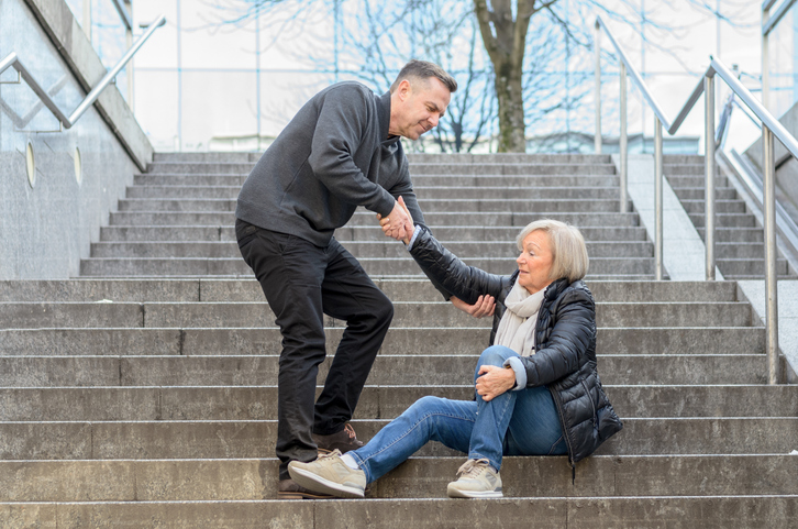 Man helping woman get up after she fell down stairs - does homeowners' insurance cover personal injury?