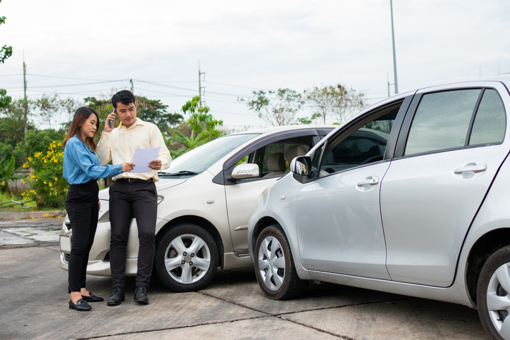 Two drivers using a smartphone to exchange information after a car accident - how do 50/50 split liability personal injury claims work