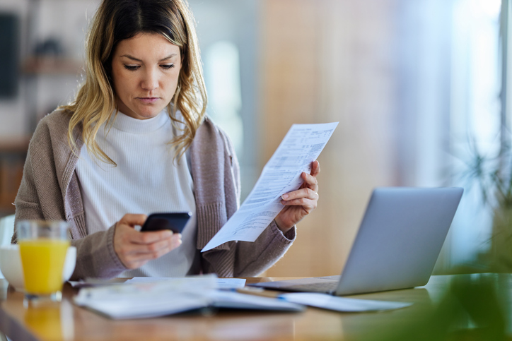 Woman using a cell phone while calculating and looking through documents - What to do if an employee is stealing from me