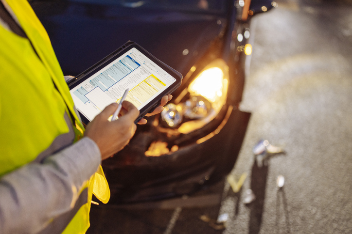 closeup of man filling accident report after car crash - what happens when a car accident claim exceeds insurance limits?
